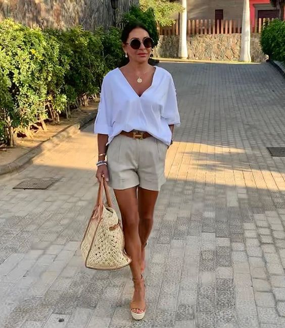 mulher usando shorts de alfaiataria e camisa branca com sandália anabela de texturas naturais